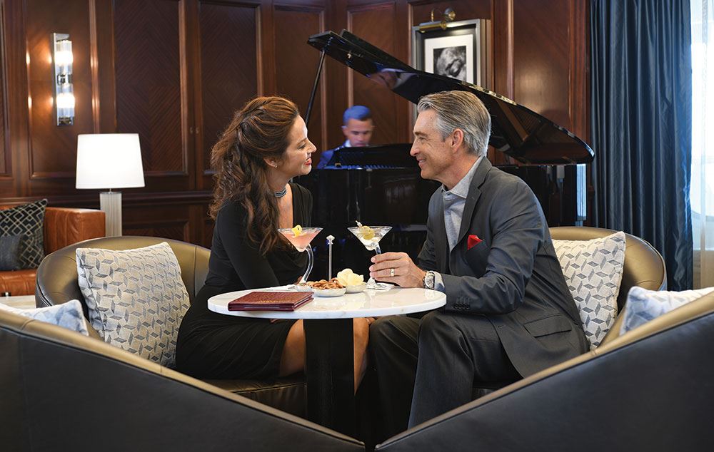 couple having martinis in Oceania cruise lounge being serenaded by piano player
