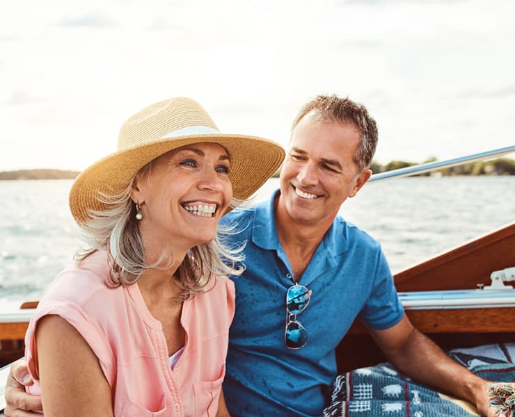 middle aged couple smiling on boat on vacation