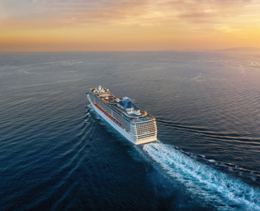 cruise ship sailing into the ocean sunset