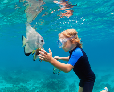young boy snorkeling with a fish